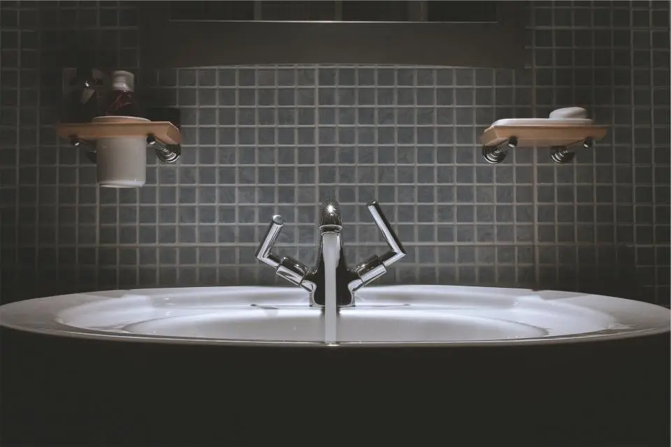 Modern bathroom basin with chrome mixer tap against dark tiles