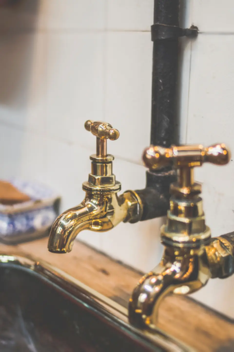 Traditional brass taps on a white tiled wall