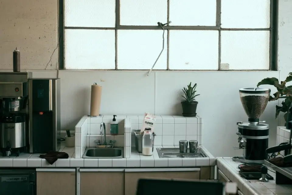 Kitchen sink under a large window with a tiled splashback