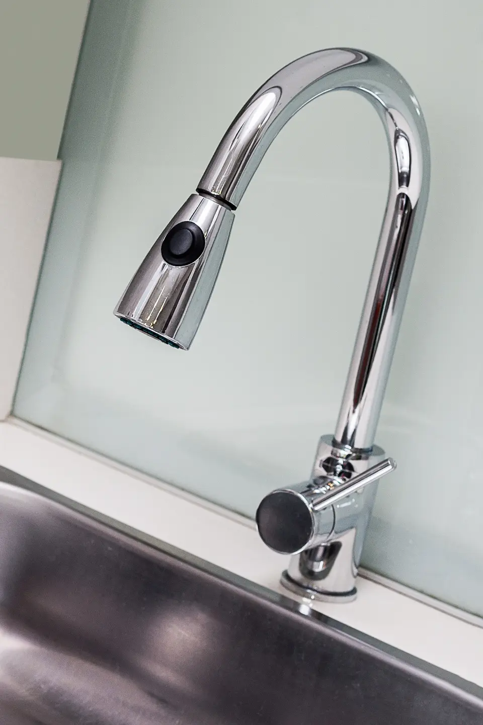Chrome pull-out kitchen tap over a white sink