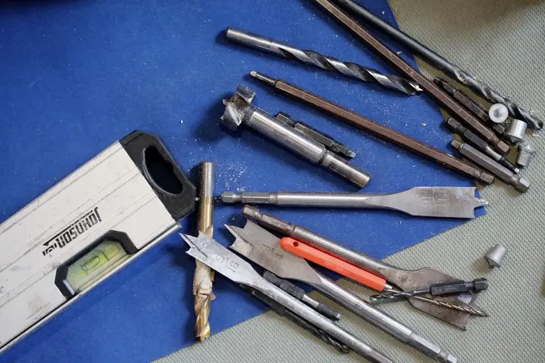 A plumber’s tools laid out on a workbench: spirit level, drill bits and fixings