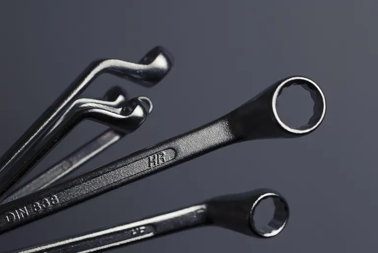 Set of steel spanners on a dark workbench